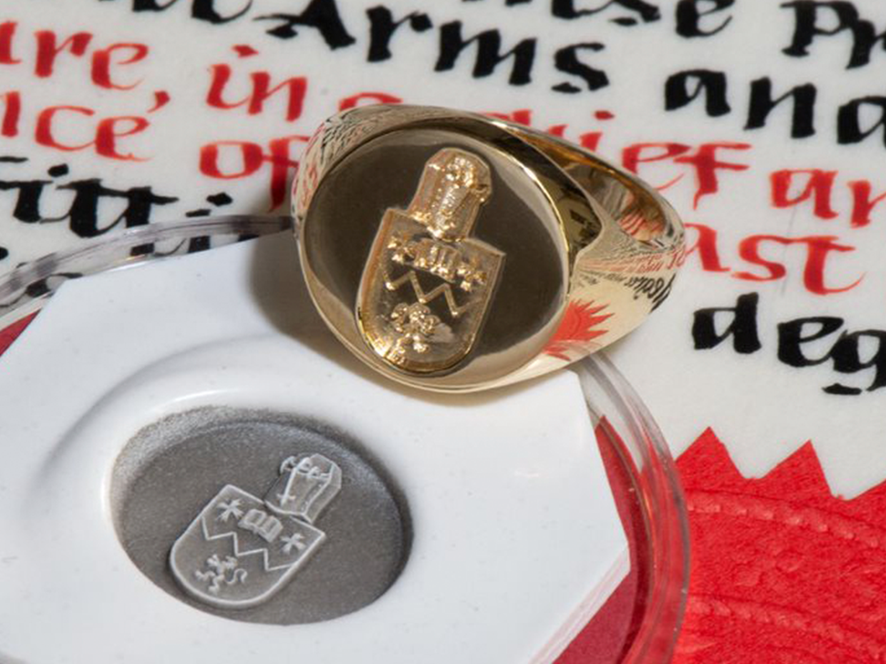 Gold signet ring with coat of arms engraving with seal on medieval calligraphy script background